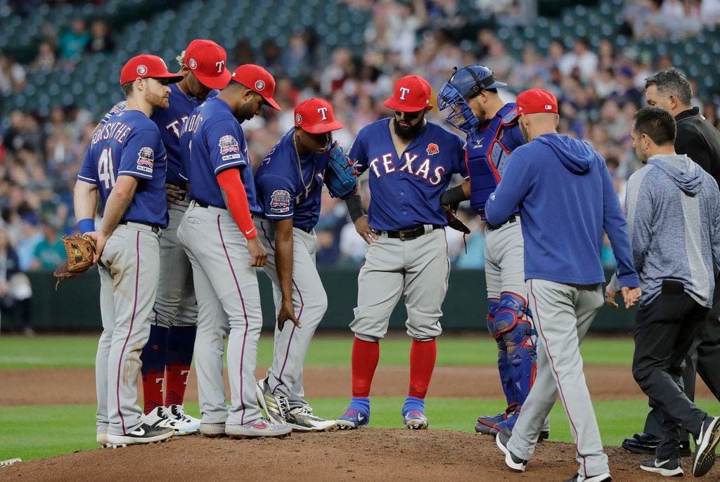 Texas Rangers relief pitcher Jose Leclerc, fourth from left, holds his right leg as members...