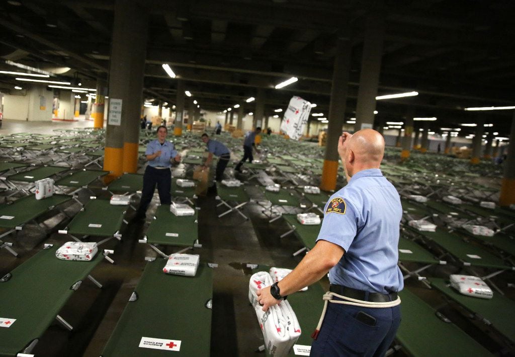 Dallas Fire-Rescue recruit David Manning tosses American Red Cross blankets onto beds to house up to 5,000 Gulf Coast residents inside the "mega shelter" at the Kay Bailey Hutchison Convention Center in Dallas on Monday, Aug. 28, 2017. Flooding from tropical storm Harvey has displaced many residents throughout the Texas Gulf Coast. (Rose Baca/The Dallas Morning News)