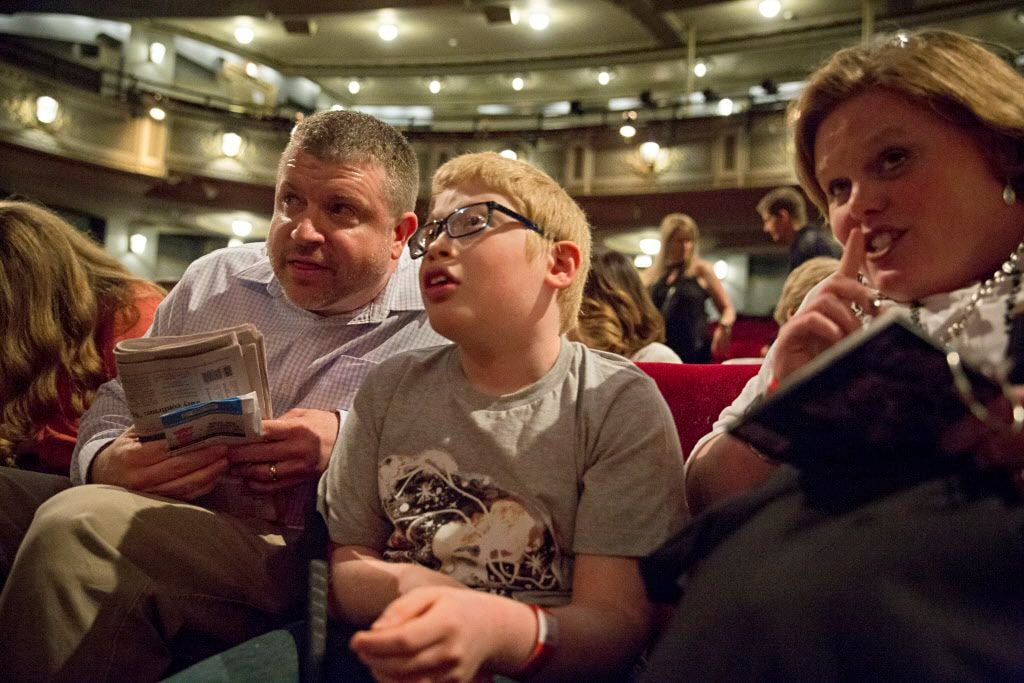 Rob and Jenn Schneider (left and right) try to quiet their son, Ben, as they listen to...