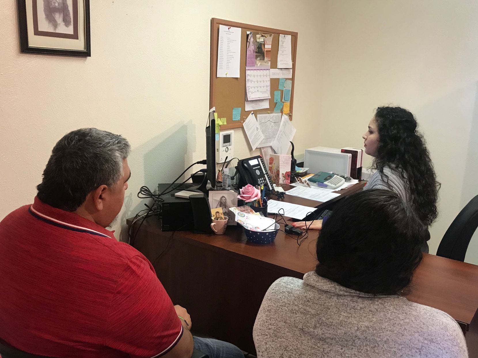 Lily Rodriguez prints out parish ID cards for Gloria and Mauricio Vega, both members of St....