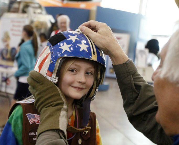 Girl Scout Estella Herrin tries on a helmet belonging to Marine pilot Tom Nollette at the...