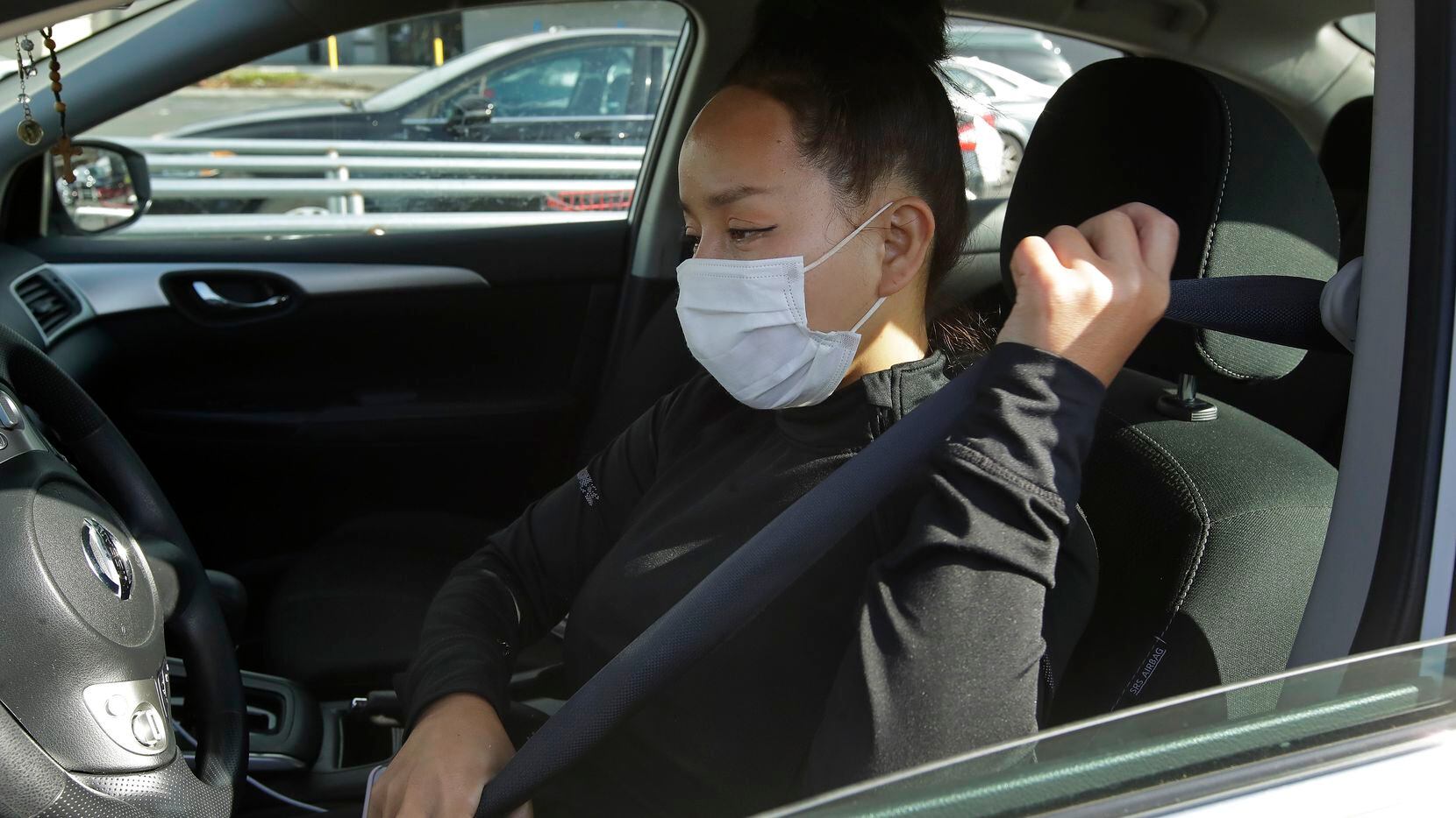 Instacart worker Saori Okawa adjusts her seatbelt on her way to deliver groceries on...