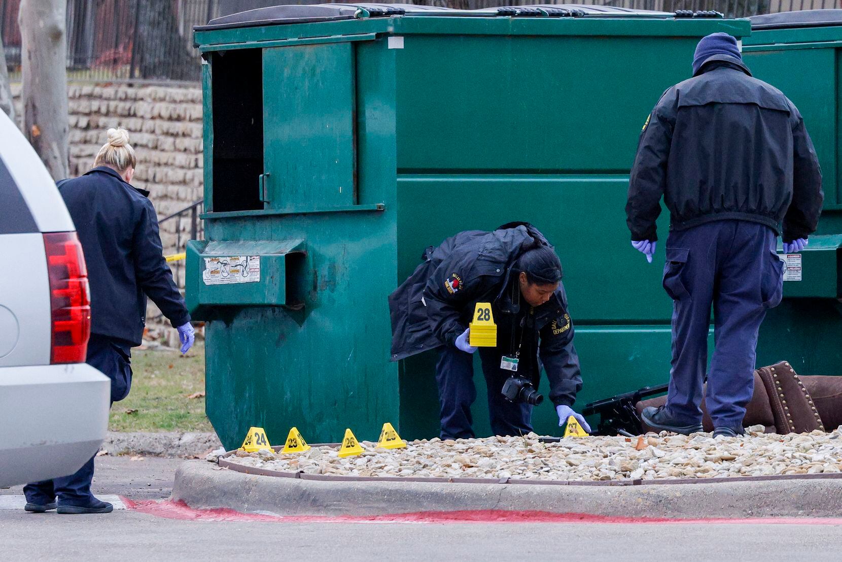 Dallas crime scene technicians place evidence markers at the scene where a Dallas police...