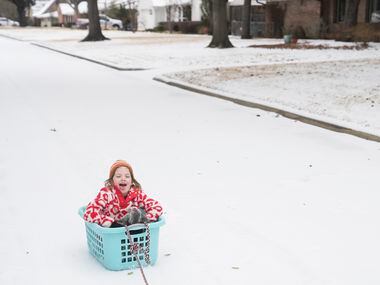 Nora Kate Strange, 6, sleds while being pulled by a truck down the street, Tuesday, Jan. 31,...