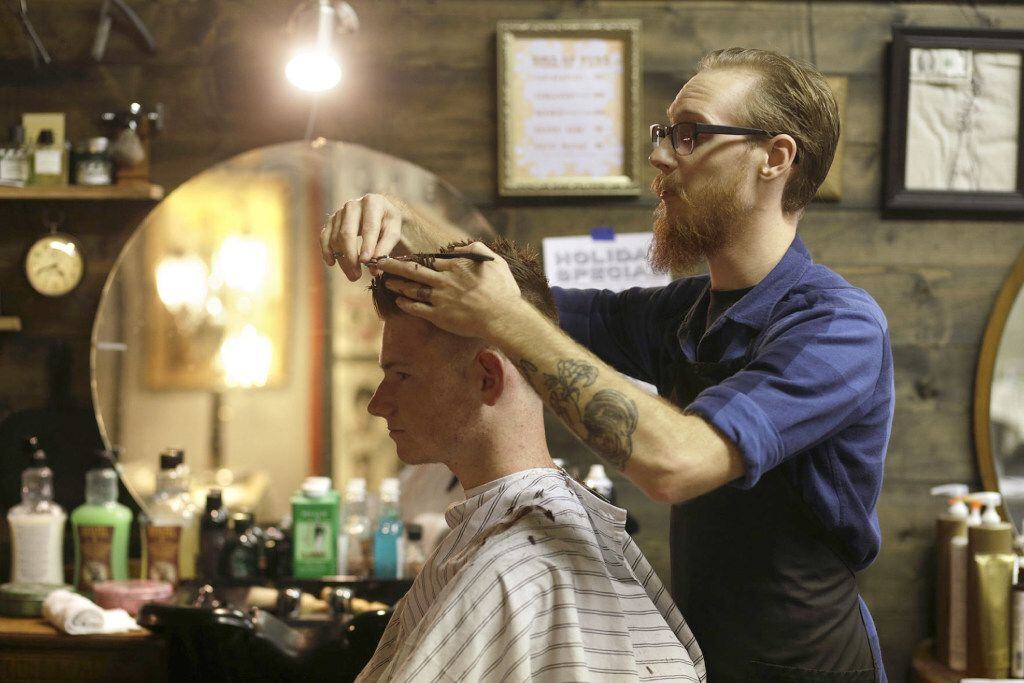 In this Nov. 29, 2016 photo, Jonathon Raby, right, cuts Brent Willmore's hair at  Burg's...