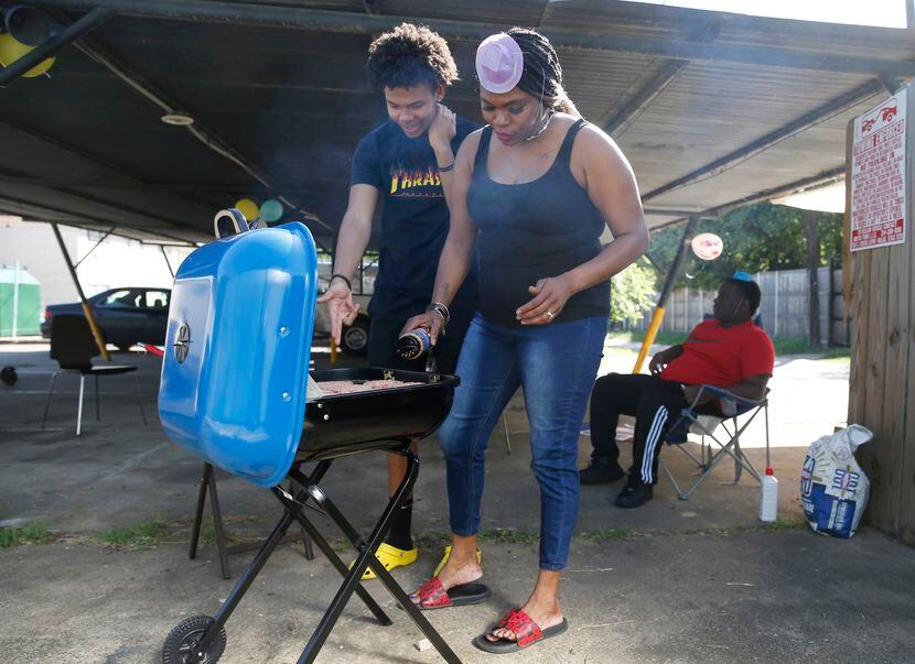Staceanne Sykes (right) and her son Kenneth Sykes, 16, tend to burgers on the grill as...