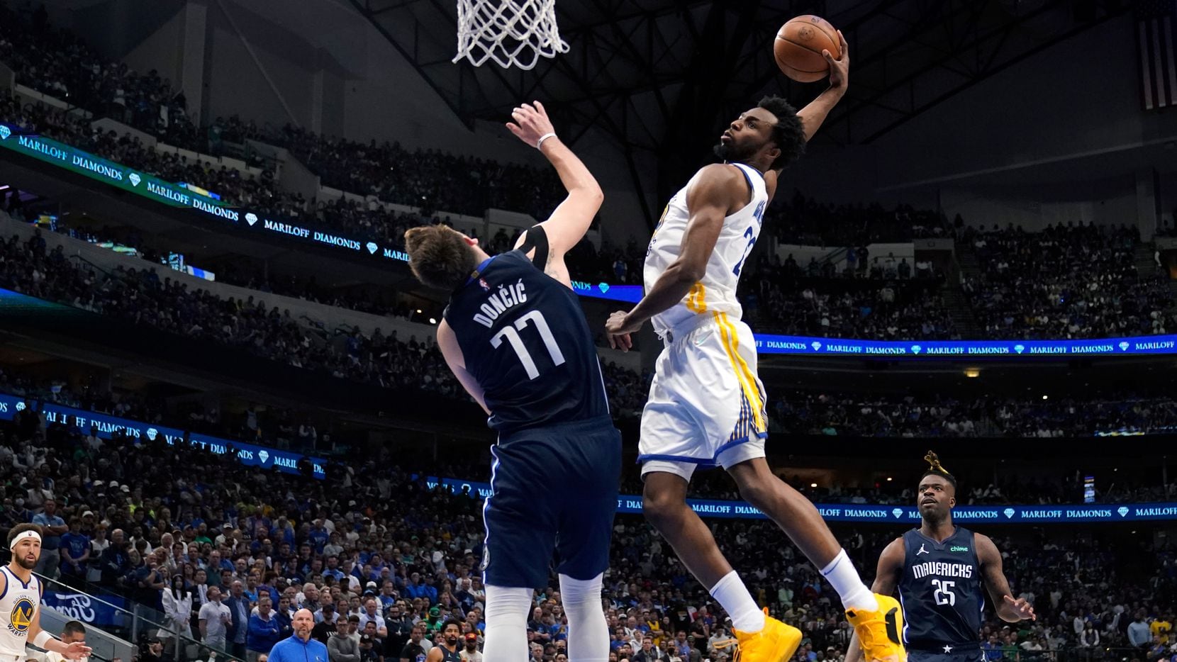 The Golden State Warriors' Andrew Wiggins dunked over the Dallas Mavericks' Luka Doncic in...