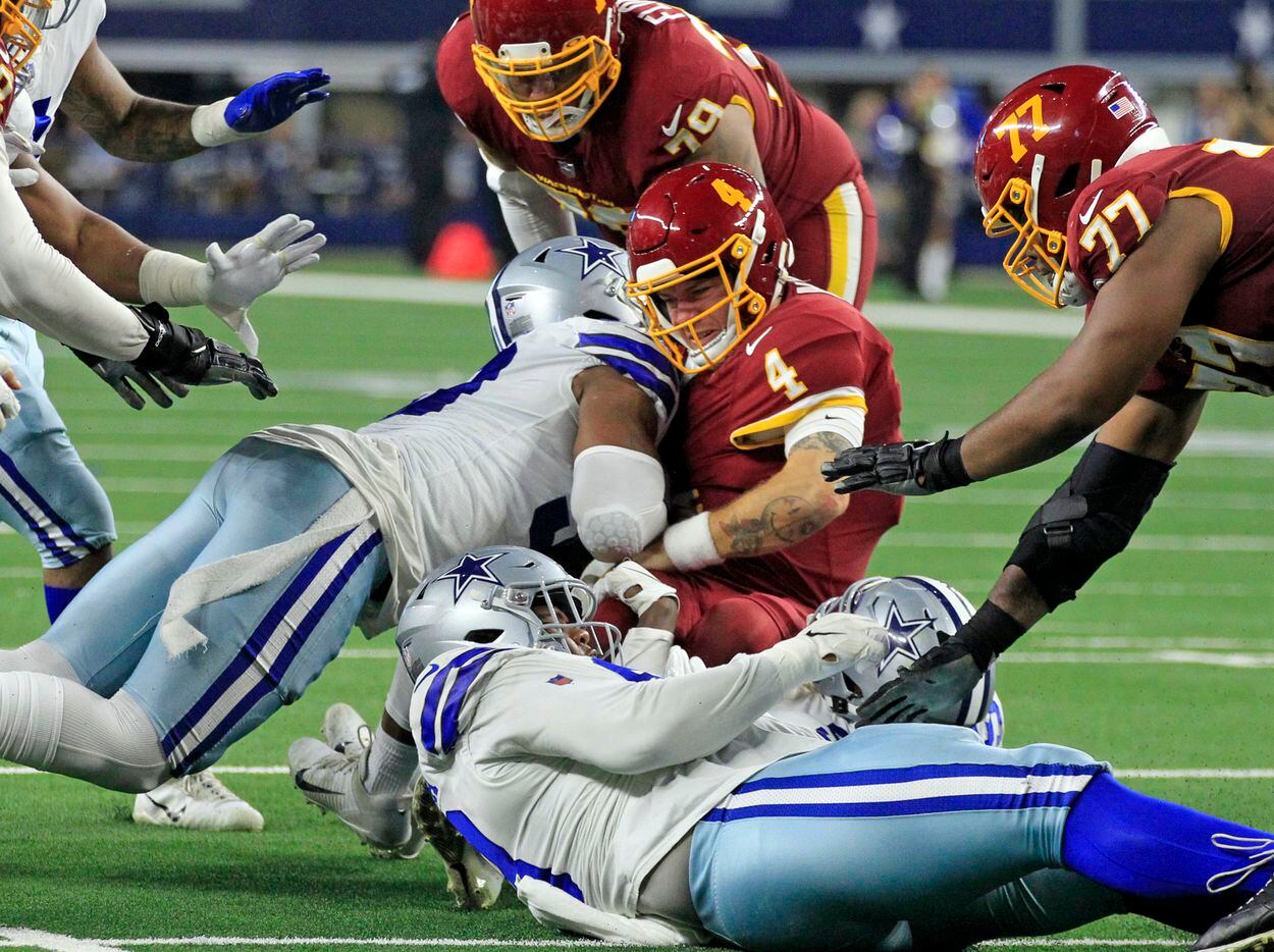 Washington Football Team quarterback Taylor Heinicke (4) is sacked by Dallas Cowboys defensive end Tarell Basham (93) and other defenders during the second half of a NFL football game at AT&T Stadium in Arlington, TX on Sunday, December 26, 2021.