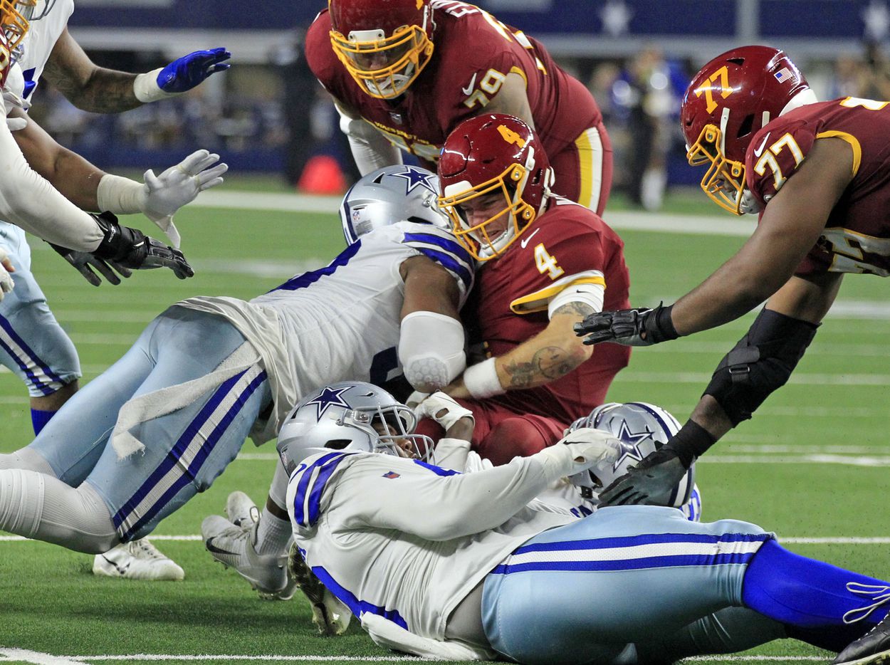 Washington Football Team quarterback Taylor Heinicke (4) is sacked by Dallas Cowboys defensive end Tarell Basham (93) and other defenders during the second half of a NFL football game at AT&T Stadium in Arlington, TX on Sunday, December 26, 2021.