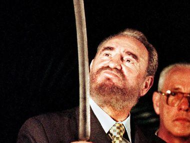 In this Aug. 24, 1998, file photo, Cuban President Fidel Castro (L) looks at a sword given...