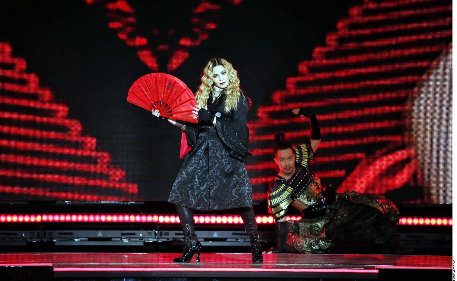 Foto de Madonna en un escenario con un abanico rojo.