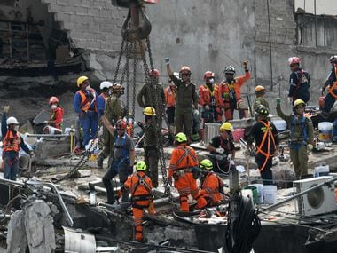 Rescue workers ask for silence during the search of survivors in a building at Colonia Roma...