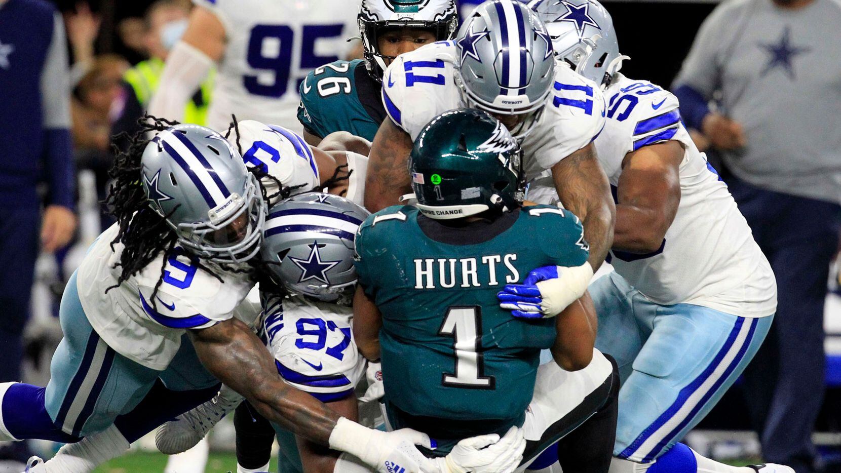 Philadelphia Eagles quarterback Jalen Hurts (1) is swarmed by Dallas Cowboys defenders, including middle linebacker Jaylon Smith (9); defensive tackle Osa Odighizuwa (97), and linebacker Micah Parsons (11) during the second half of a NFL football game at AT&T Stadium in Arlington on Monday, September 27, 2021.