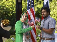Tanjima Akhtar and her son, Seean Hossain, hold flags while taking a photo after the Oath of...