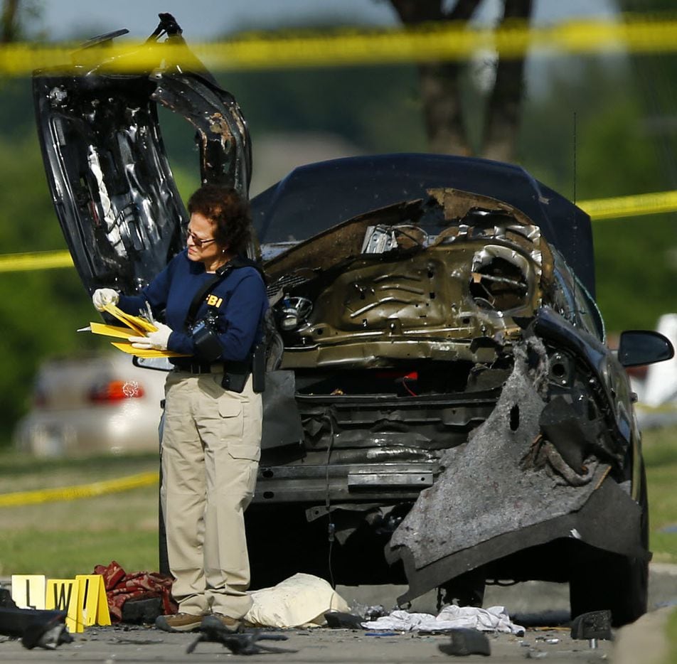 A FBI Evidence Response team member picks up yellow markers after collecting evidence near...