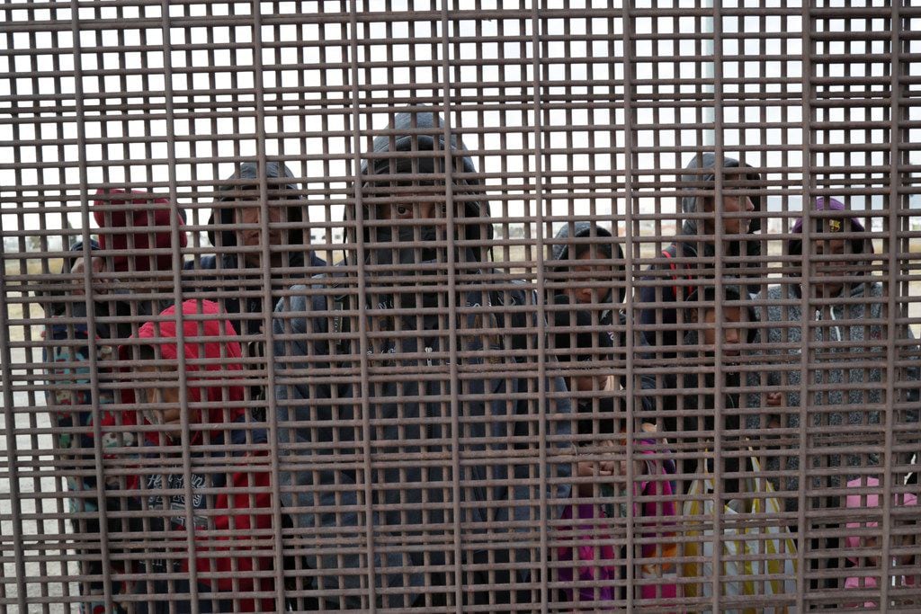 Central American immigrants stand at the U.S.-Mexico border fence after crossing the Rio...