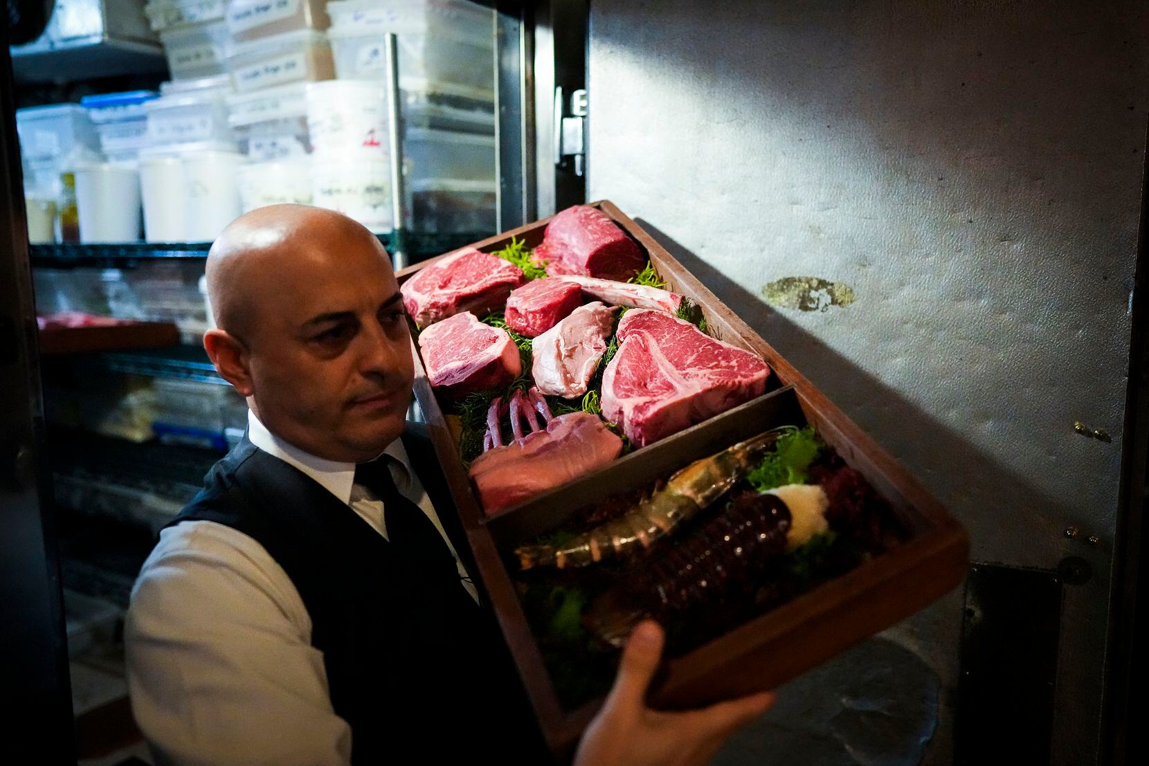Benny carries a display of steaks and seafood from a refrigerator at Nick & Sam's.