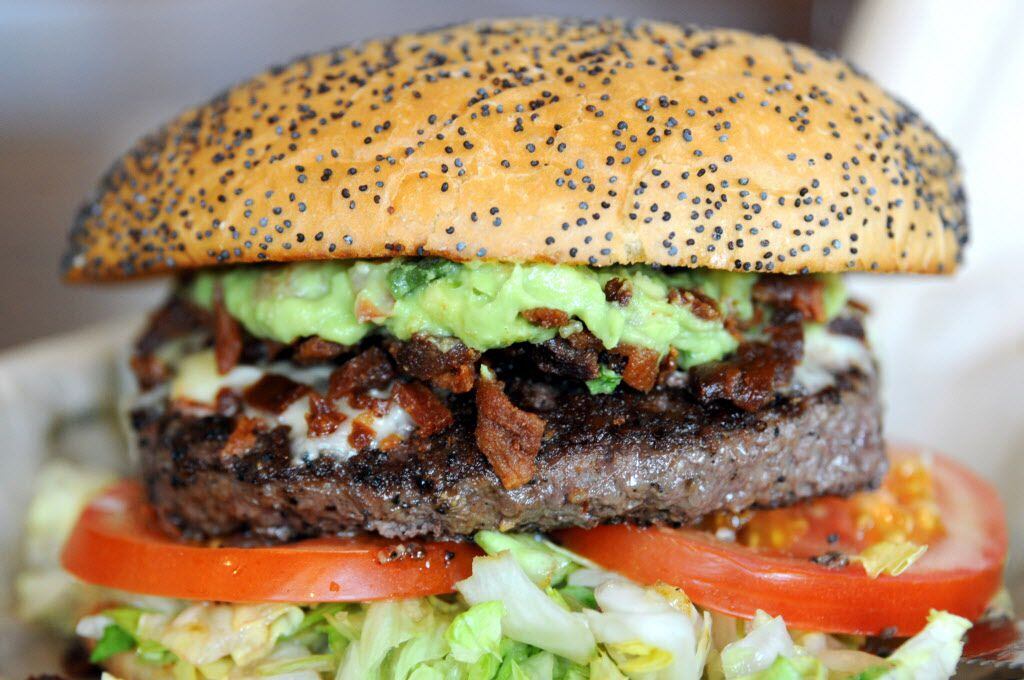 The bacon guacamole burger is served on a poppy seed bun with crumbled bacon, guacamole,...