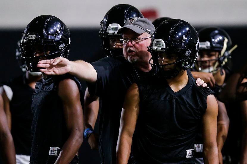 Euless Trinity coach Chris Jensen gives instructions to his players during a varsity...