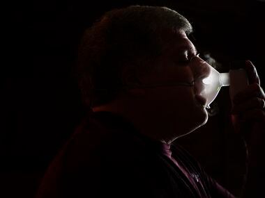 In a new nighttime ritual, Michael Hoffman breaths from a portable nebulizer to hydrate his ...