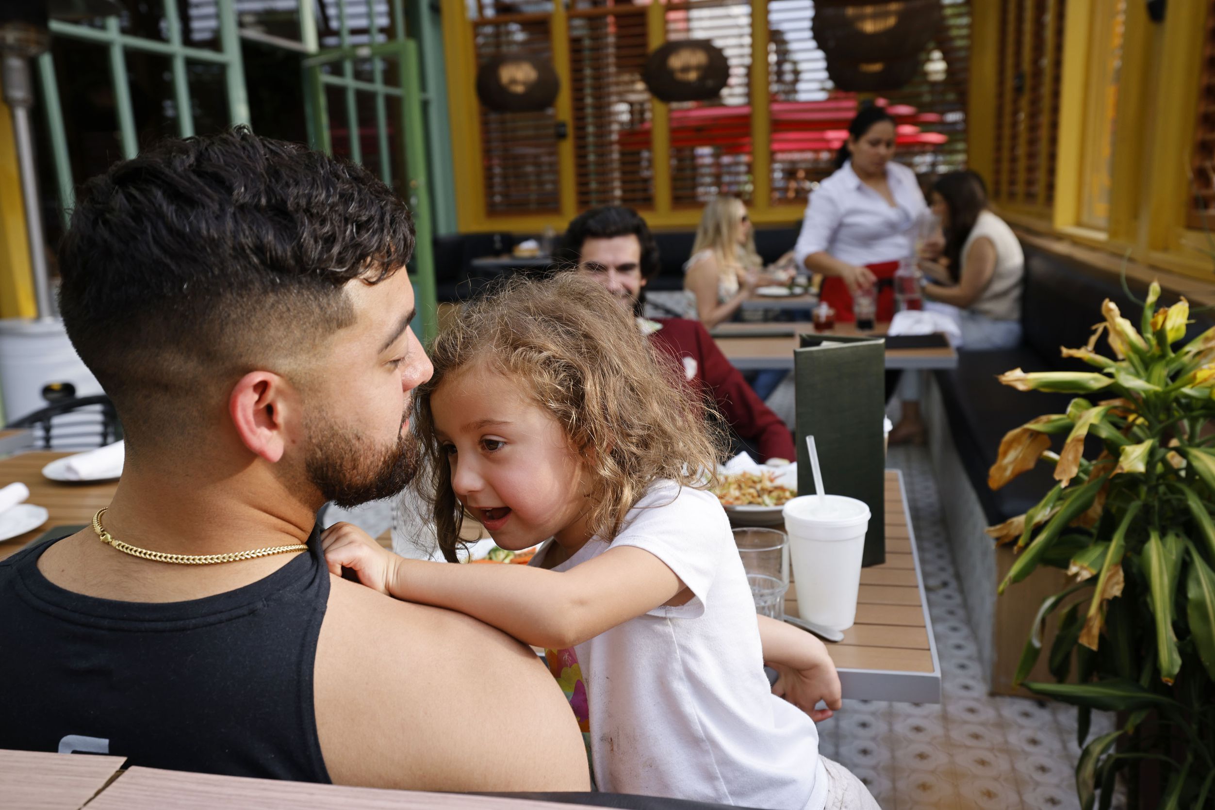 Pete Castro of Dallas, left, and his daughter Maya, 4, have dinner with his friend Michael...