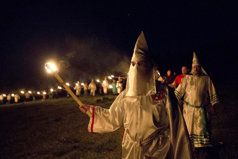 Integrantes del Ku Klux Klan, o KKK, incencian cruces luego de un mitin de supremacía blanca...