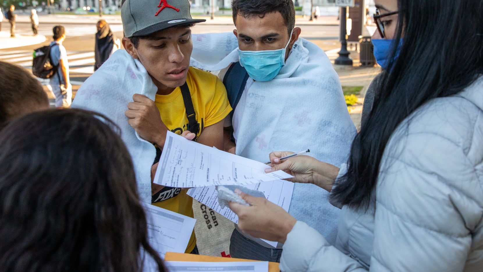 Volunteers help migrants organize their paperwork after they arrived on one of three buses...