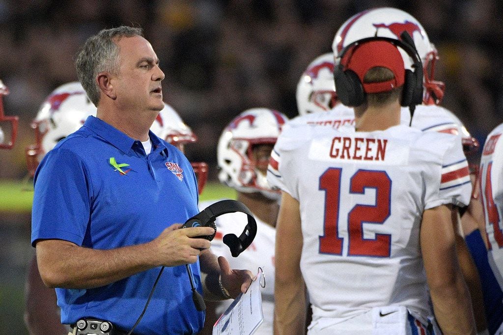 SMU head coach Sonny Dykes, left, talks to his players during a timeout in the first half of...