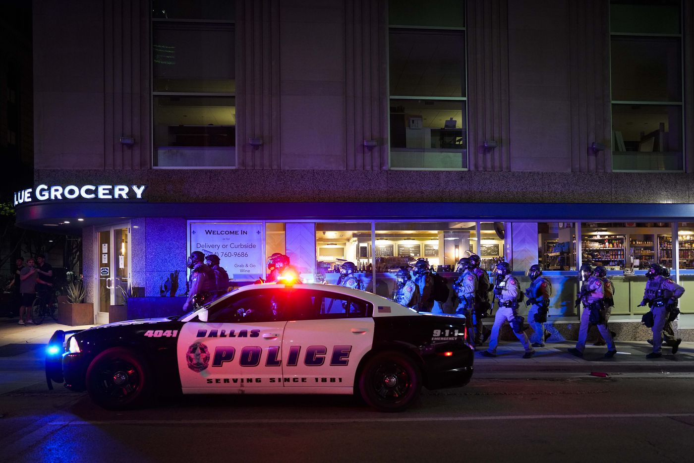 A group of Texas Department of Public Safety troopers moves up Ervay Street as they work to...