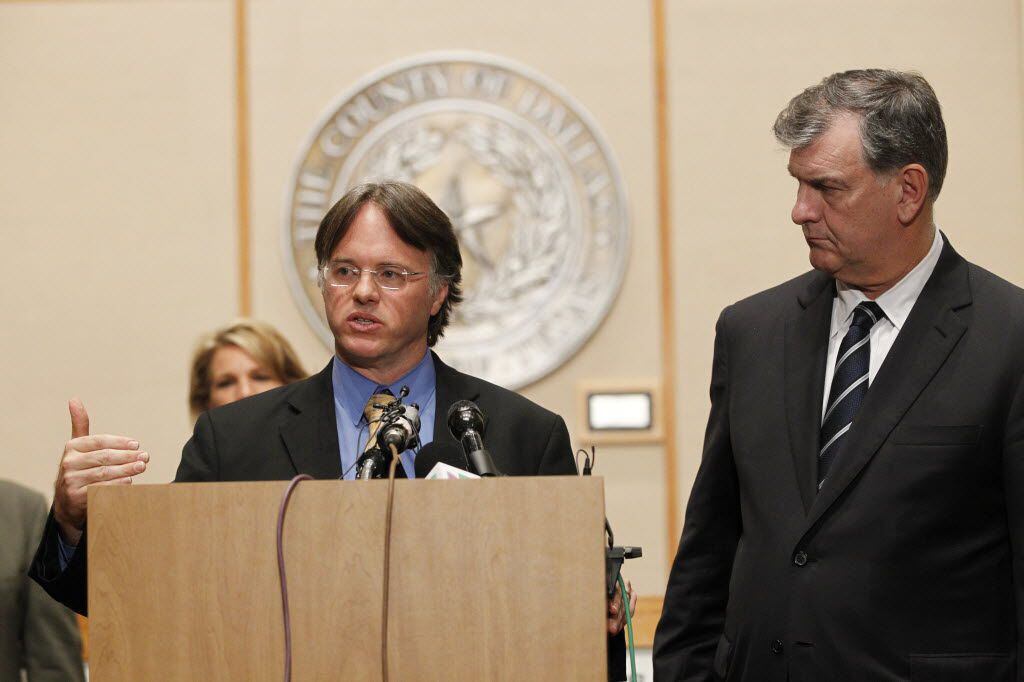 Dr. David Lakey speaks as Dallas Mayor Mike Rawlings looks on during a press conference...