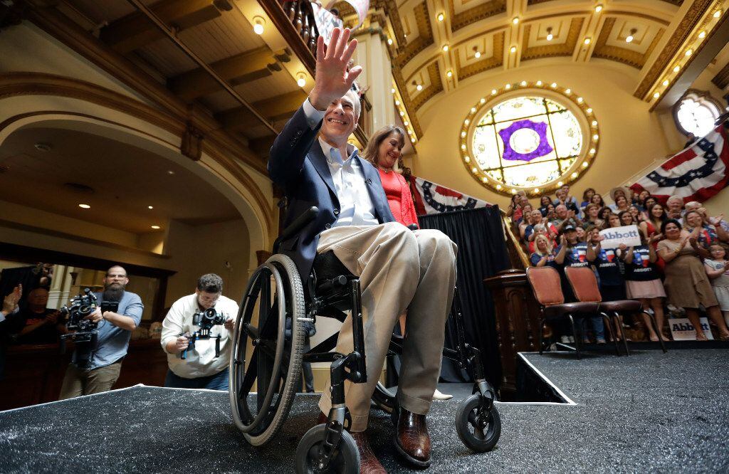 Texas Gov. Greg Abbott waves to supporters as he and his wife, Cecilia, arrive for an event...