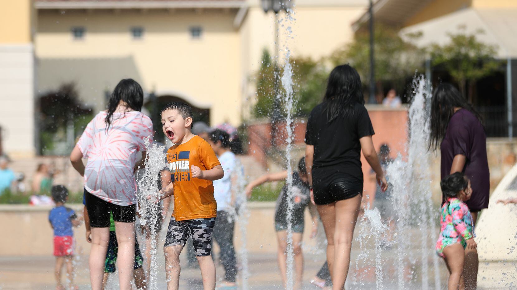 Niños se refrescan en la fuente de agua en The Harbor Rockwall Texas, el 5 de julio de 2021.