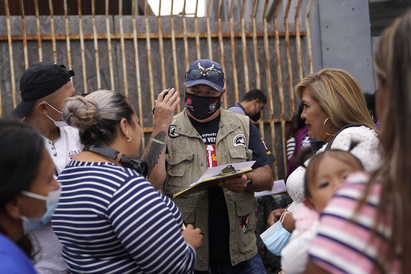 El activista Robert Vivar (centro) habla en Tijuana (México) con migrantes que esperan...
