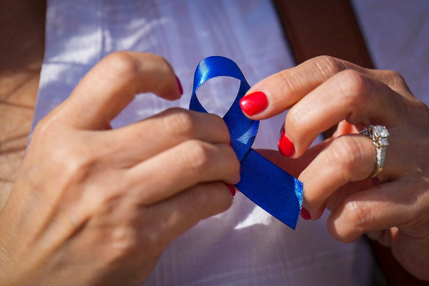 A woman pins a blue ribbon for child abuse awareness on her blouse as she waits in line to...