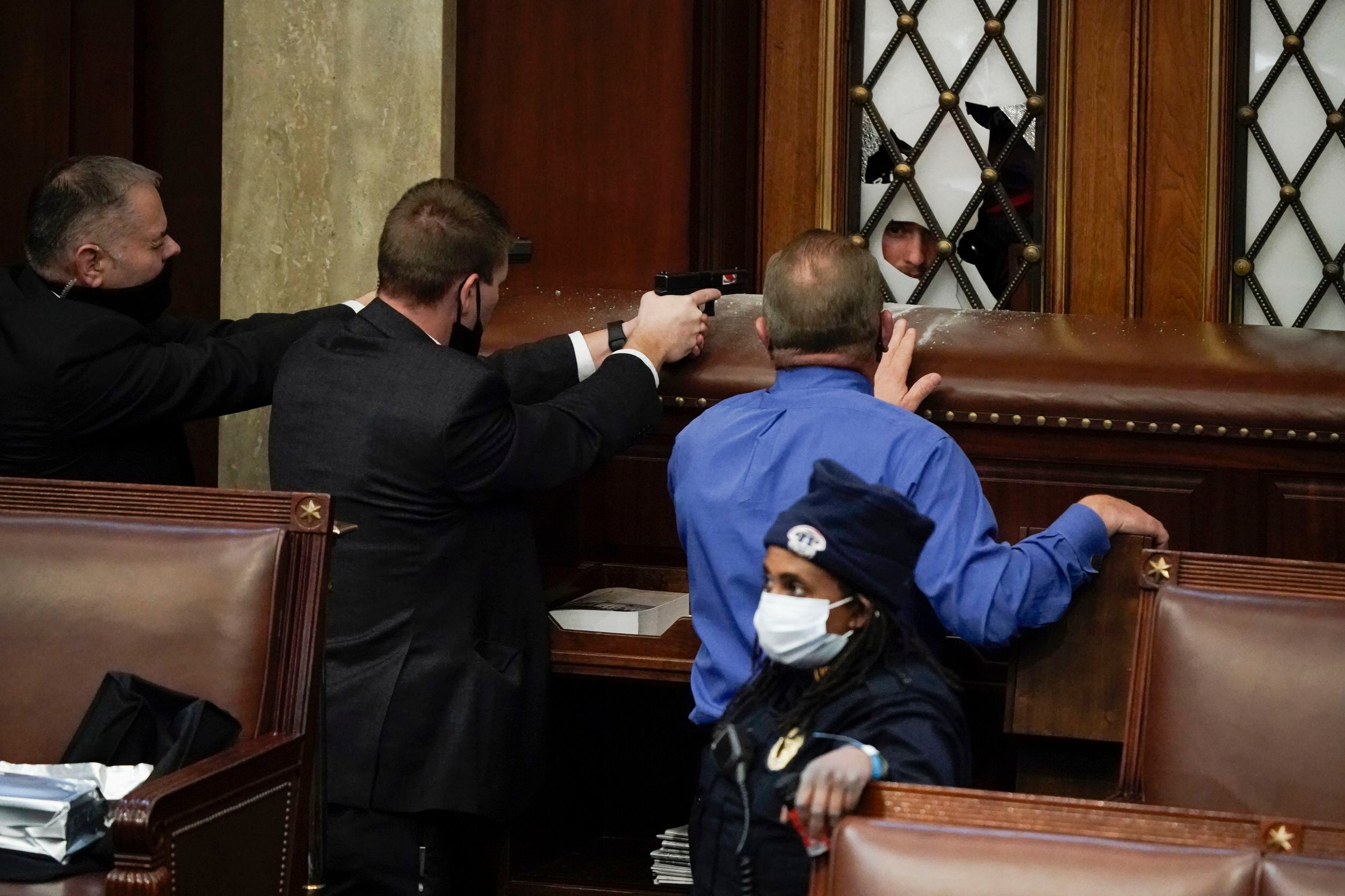 Police with guns drawn watch as protesters try to break into the House Chamber at the U.S....