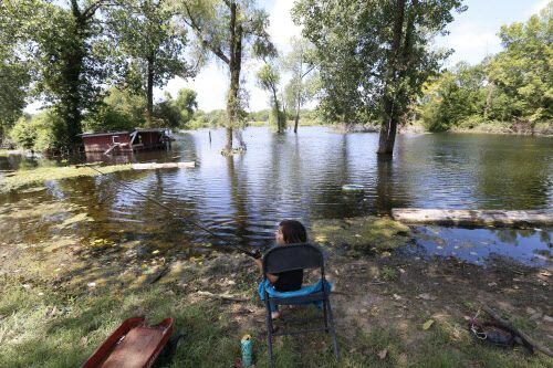 Noah Torres, 4, casts his fishing pole in the flooded backyard of his house, which is...