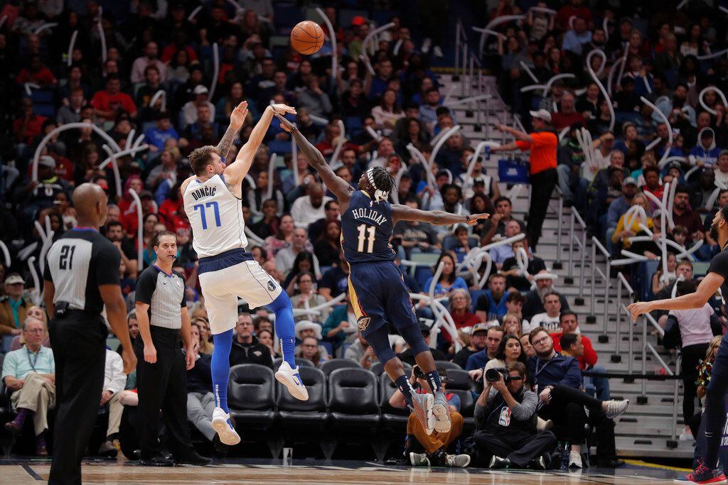 Dallas Mavericks forward Luka Doncic (77) shoots over New Orleans Pelicans guard Jrue Holiday (11) during the second half of an NBA basketball game in New Orleans, Friday, Dec. 28, 2018. The Pelicans won 114-112. (AP Photo/Gerald Herbert)