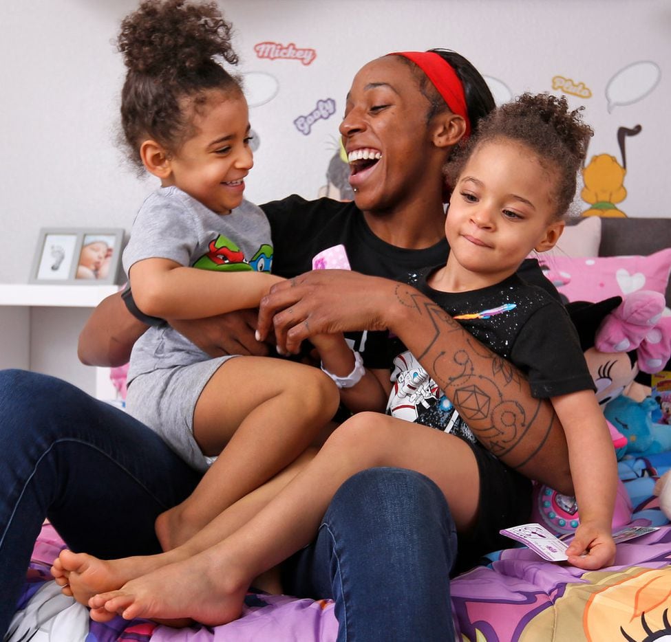 Dallas Wings' player Glory Johnson plays with her twin daughters Solei, left, and Ava in...