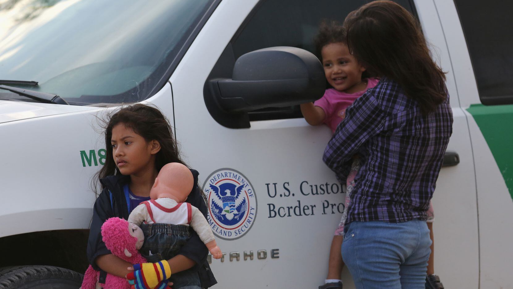Central American immigrants await transportation to a U.S. Border Patrol processing center...