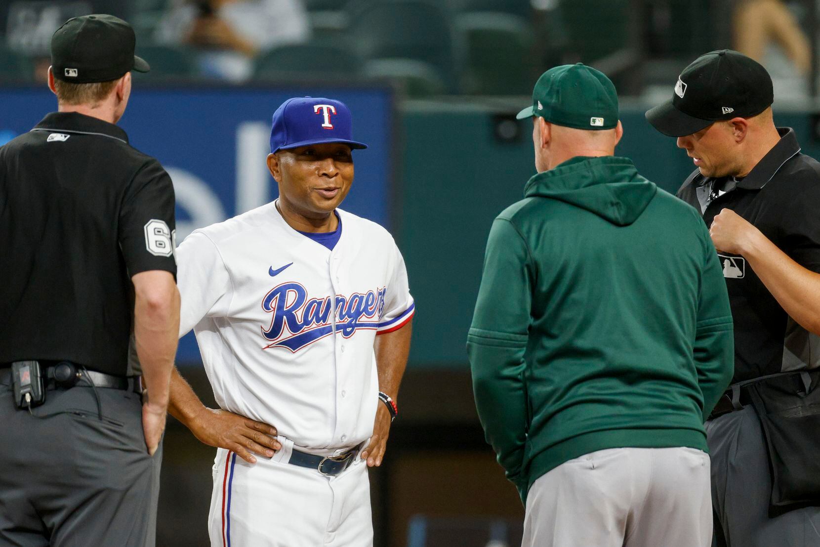 Texas Rangers interim manager Tony Beasley (27) talks with the umpires and Oakland Athletics...