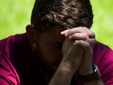 Dakota Loupe bows his head in prayer during a day of remembrance for last year's police...