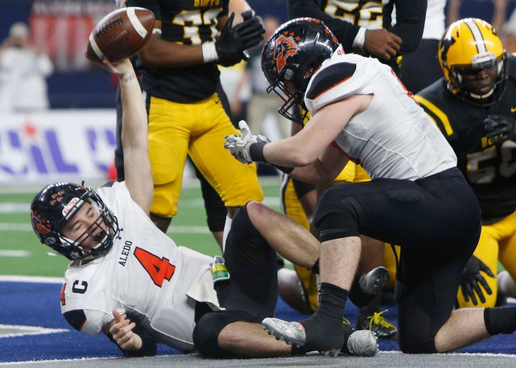 Aledo quarterback Jake Bishop (4) raises the ball over his head after lunging into the end...