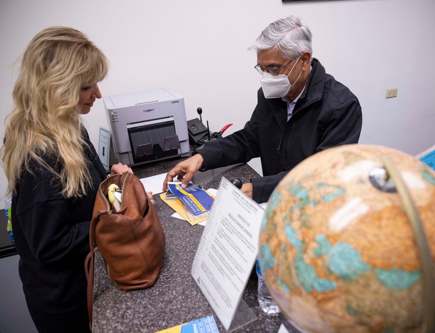 Amy Kirkland (left) of McKinney receives her passport before her trip to Canada from Madan Goyal on Wednesday, Nov. 3, 2021, at Passport and Visa Express in Plano. (Juan Figueroa/The Dallas Morning News)