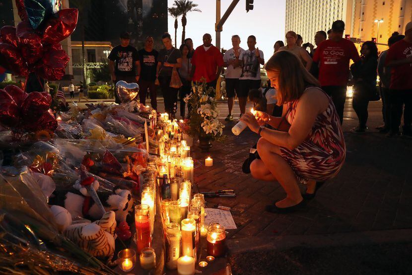A woman lights a candle on Oct. 4 at a sidewalk memorial to victims of the mass shooting. 