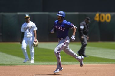 Texas Rangers' Marcus Semien, center, runs the bases after hitting a solo home run against...