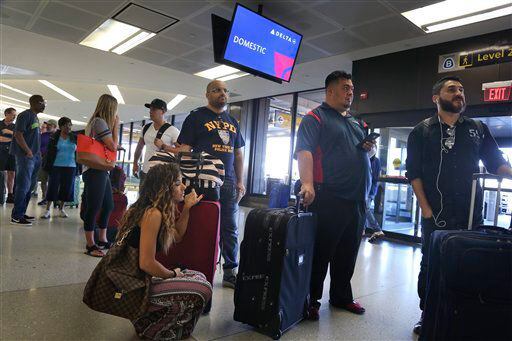 Pasajeros de Delta hacen fila ffrente a un mostrador de boletos en el aeropuerto...
