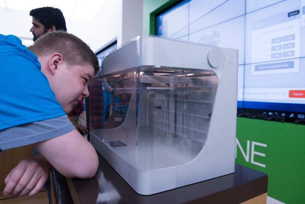 Michael Susens watches as a 3d printer builds a part of wind turbine he helped design during...