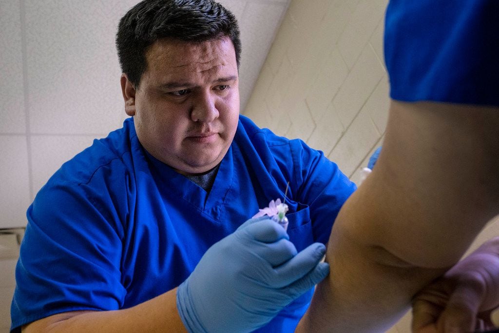 Student Asael Codiz draws blood from Miguel Valdez at West Dallas Community Church in Dallas.