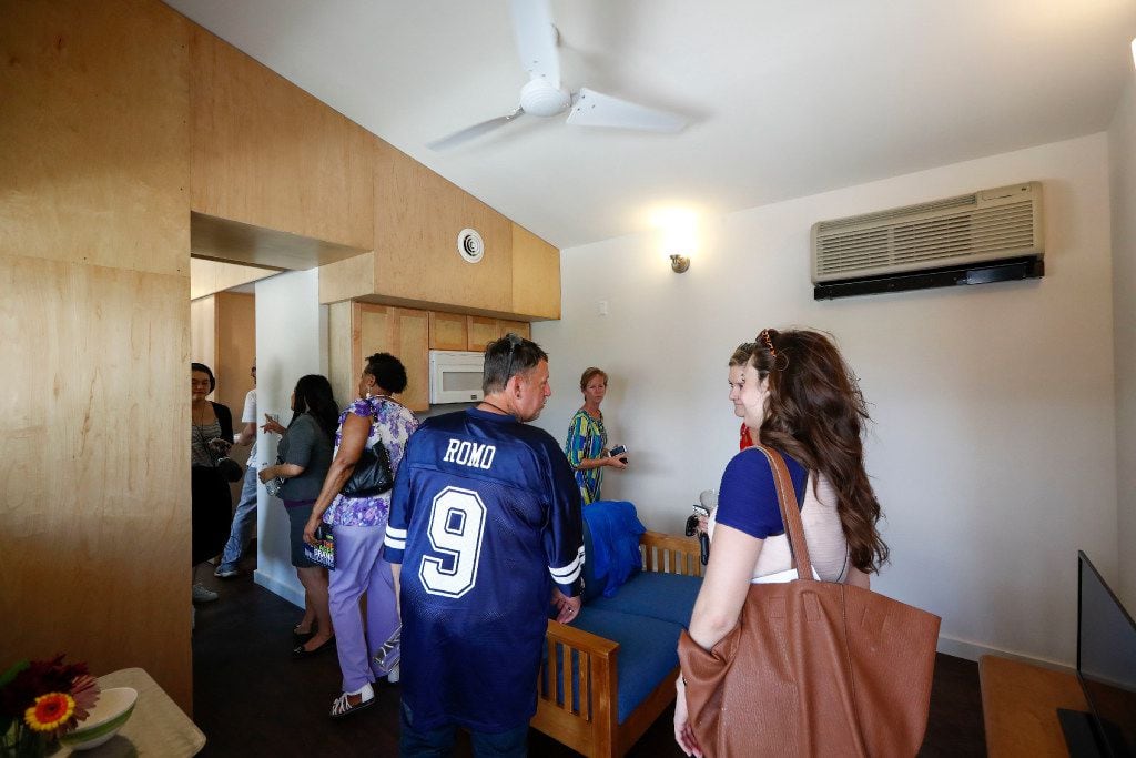People tour the interior of the housing units during the opening ceremony at Cottages at...