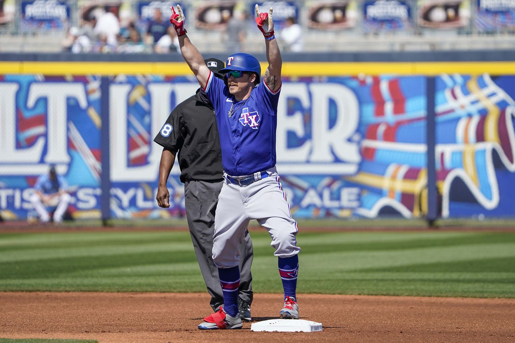 Texas Rangers infielder Brock Holt celebrates at second base after hitting a leadoff double during the first inning of a spring training game against the Seattle Mariners at Peoria Sports Complex on Wednesday, March 10, 2021, in Peoria, Ariz.